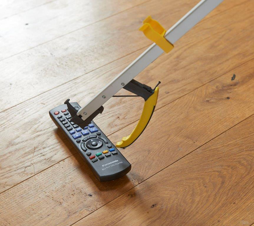 the image shows a close up of a classic pro reacher picking up a tv remote control