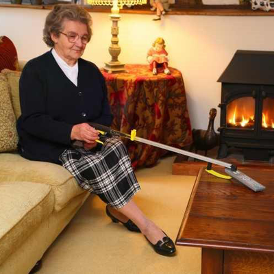 the image shows a woman using the classic pro reacher to pick up a tv remote